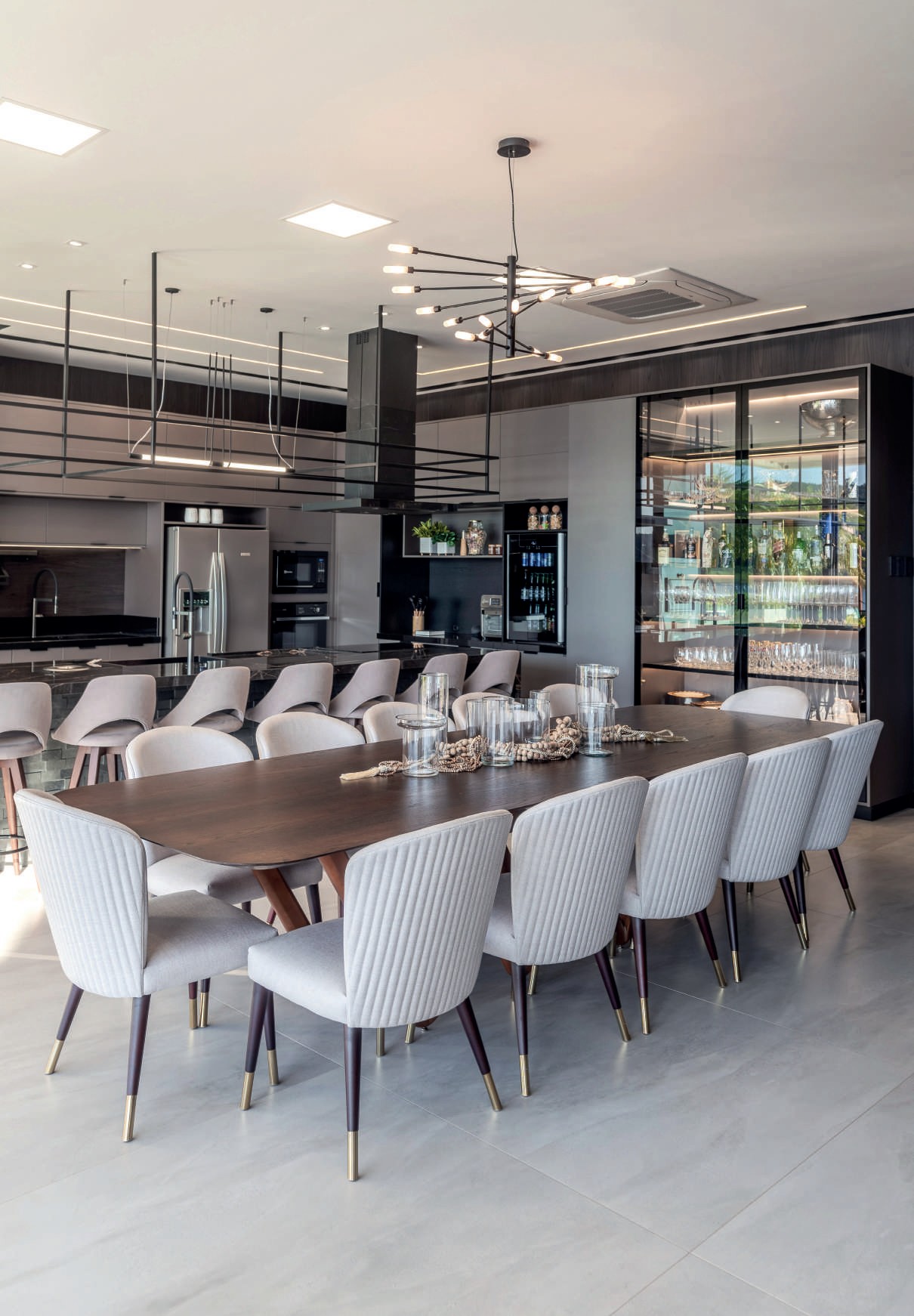 Sala de jantar com mesa de madeira, adega climatizada e cozinha ao fundo