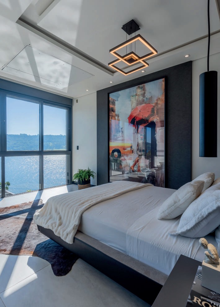 Suíte master com cama voltada para a vista do lago